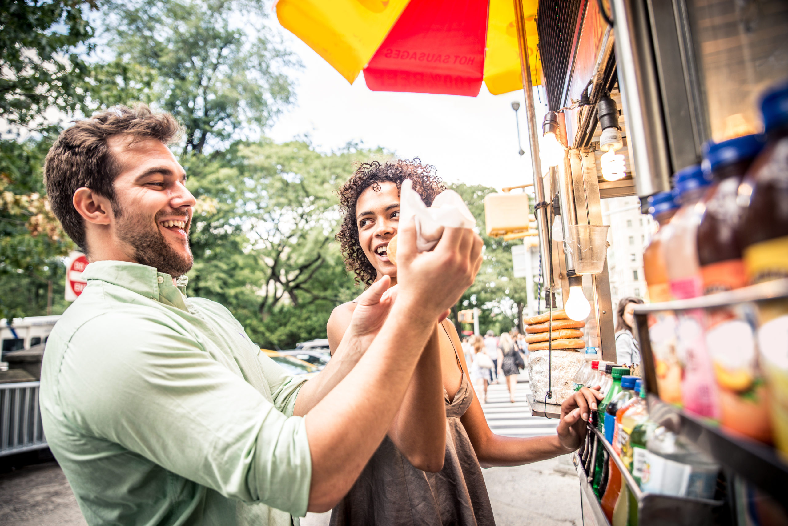 Happy couple buying hot dogs at a food stand looks forward to digging into a hearty meal