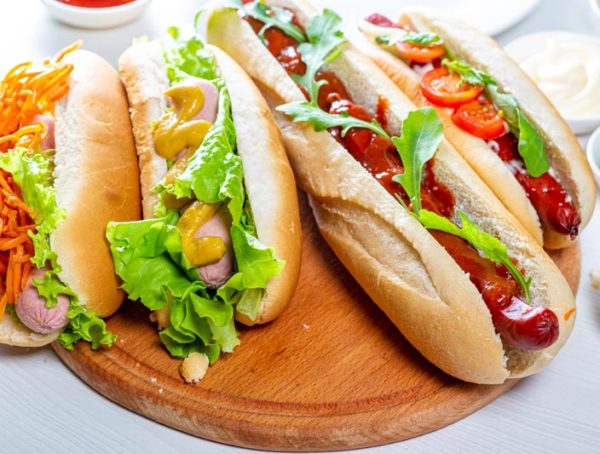 Hot dogs fully loaded with assorted toppings on a tray. Food background.