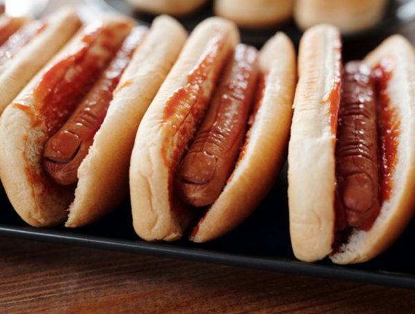 Hotdog sandwiches on black tray.