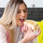 Happy woman eating hot dog.