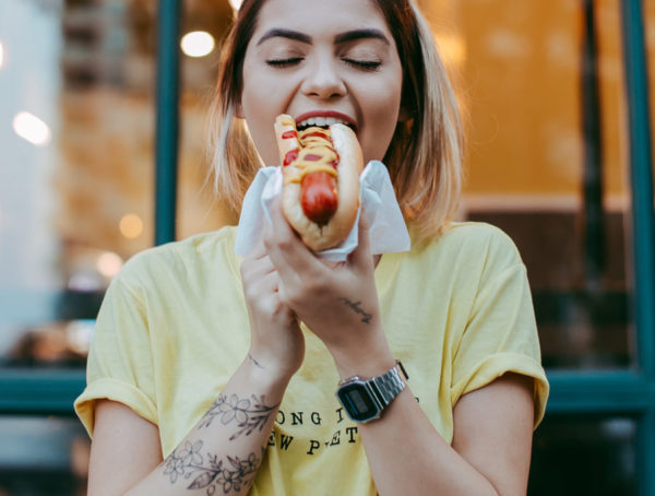 A photo of a woman eating a hot dog.